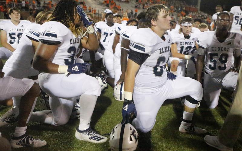 Blue Devils (L-R) Tamar Burton, Seth Capps and A.J. German take a knee to listen to head coach Brad Waggoner after losing to Hart County Friday night Aug. 23 in Hartwell. (Photo by Cary Best)