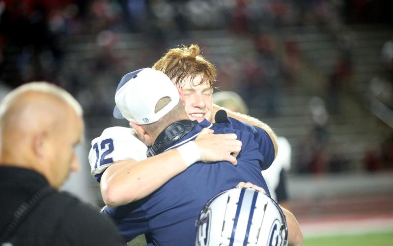 quarterback Braydon Scarborough hugs Head Coach Shannon Jarvis following Elbert’s 21-20 win over Harlem. Scarborough led the Devil offense with 396-yards passing in the game. (Photo by Wells)