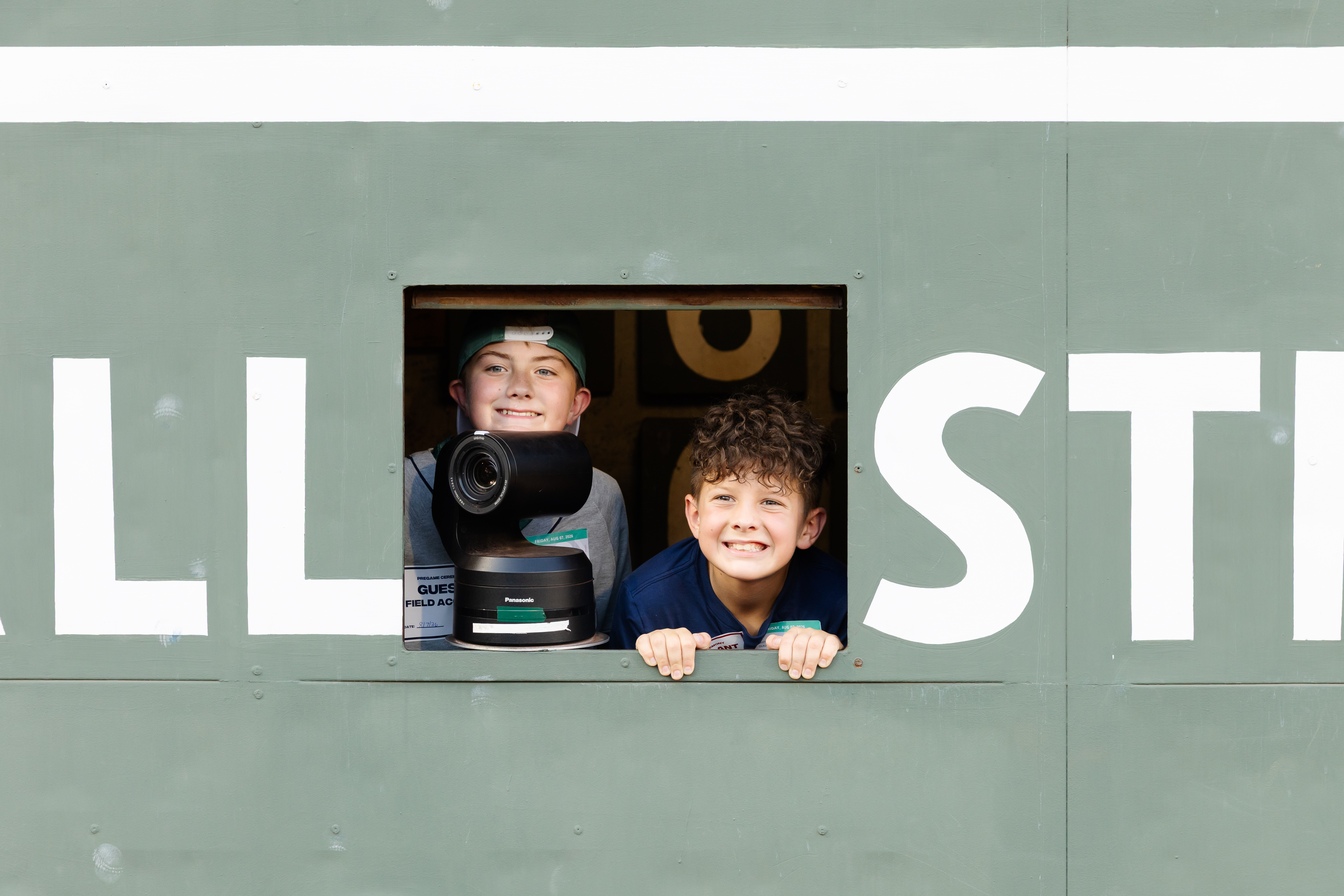 Paxton Glaude (right) and Spencer Etheridge (left) peek out from behind the historic Green Monster at Fenway Park. (Photo by Dream On 3)