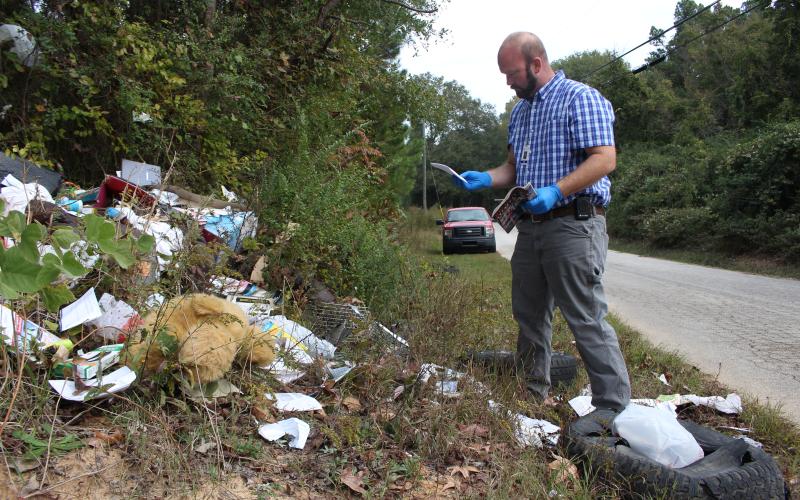 Investigation in progress – Allen Hulme looks for clues after he finds dumping in a remote area of Elbert County. (Photo by Scoggins)