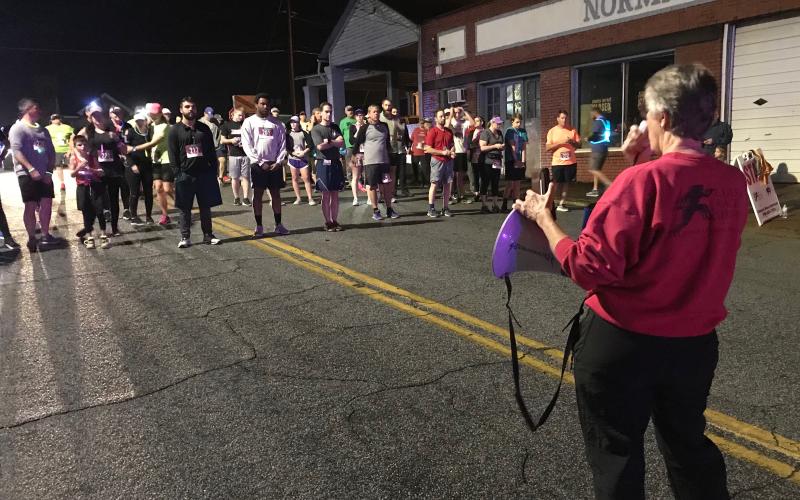 Carol Baker, whose company (Classic Race Services) times runners for the Twilight Stroll, gives instructions to runners before the 5K start. (Photo by Jones)