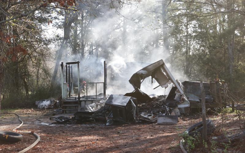 Remnants of a structure fire at 1531 Dunn-Worley Road smolder as Elbert County firemen walk around the structure on Thursday, March 12. The fire, listed as a “structure fire/arson” in the incident report from the Elbert County Sheriff’s Office, occurred at 9:22 a.m.  The Georgia Fire Marshal’s office said an Elbert County woman has been charged with causing the fire. (Photo by Scoggins).