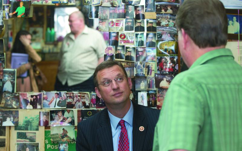 Doug Collins, shown in an Elberton Star file photo talking with Anderson Barber Shop owner Doug Anderson, talked to members of the Elbert County Chamber of Commerce in a conference call last week. (Photo by Best)