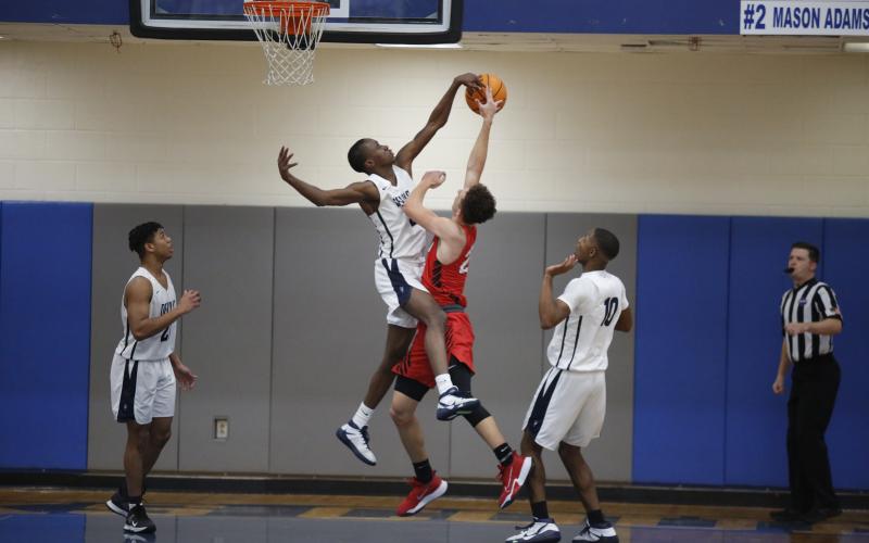 Sophomore Trustin Allen (left) and junior Jamil Burton (right) watch as senior Korbin Eberhardt (center) blocks a layup from a Rabun County Wildcat during the Devils’ competition against Rabun County during the Region 8-AA Tournament at Banks County Saturday, Feb. 13. (Photo by Scoggins)