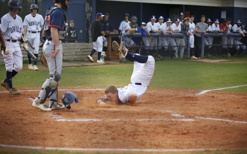 Sophomore Skylar Bray eats dirt with his helmet flying off as he slides into home in the bottom of the first during the Diamond Devils’ competition against Habersham Central Tuesday, March 23. (Photo by Scoggins)