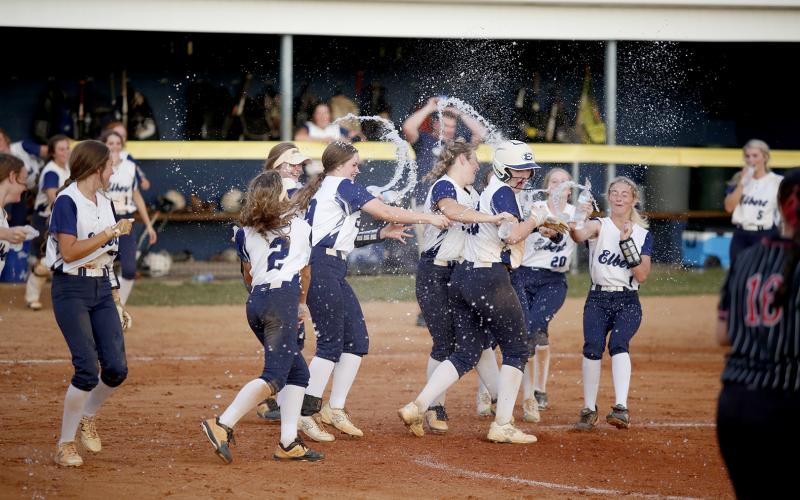 Lady Devil Lilly Ray (third from right) is rushed by a swarm of Lady Devil teammates with bottles of water after she singled on a hard ground ball and teammate Ava Lunsford scored the final run for the Lady Devils during the Sept. 9 10-2 region victory over Rabun County. (Photo by Scoggins)