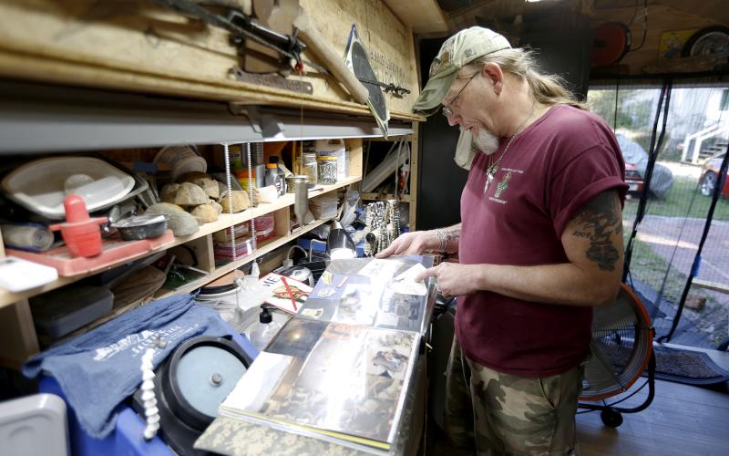 Allen Cartledge looks through a scrapbook from one of his deployments in a shed he has turned into his workshop and “sanctuary” in his backyard. Cartledge was deployed in Iraq from 2009-2010 and in Afghanistan from 2013-2014. (Photo by Scoggins)