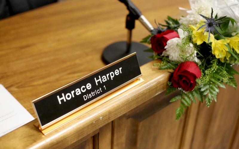 Flowers were placed at Commissioner Horace Harper’s empty seat during Monday night’s regular commission meeting. (Photo by Scoggins)