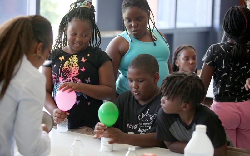 Children in the Elbert County Community Friends’ summer activities program received a lesson in chemistry from Elbert County’s own chemist, Pamela Brown, Monday, June 20 at the Mill Street Gym. Brown performed an experiment that allowed children to blow up balloons by having baking soda in the balloons mix with vinegar in a recycled water bottle. Elbert County Community Friends hosted a day of youth activities at the gym as part of the weekend’s Juneteenth celebration. (Photo by Scoggins)