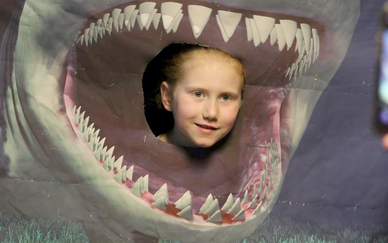 Alaina Caster poses between the teeth of shark inside the “Oceans of Possibility” mobile museum outside the Elbert County Public Library Friday, June 24. Right,