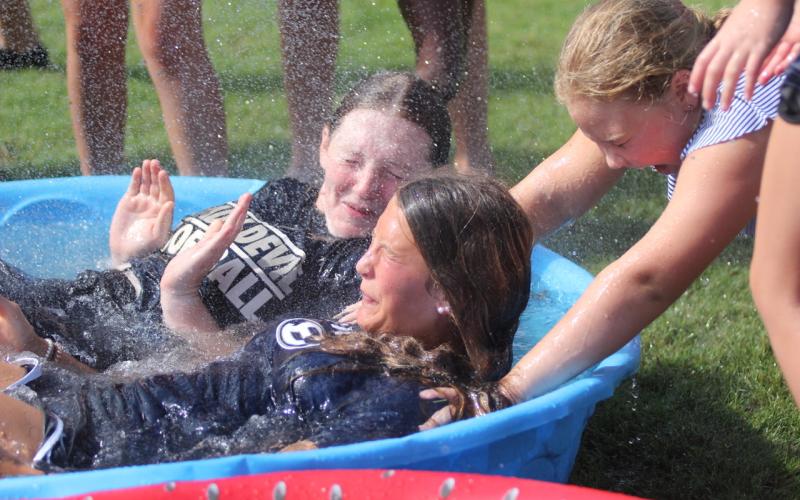 Lady Devils softball camper Karson McKeller (right) helps hold down Lady Devils Lilly Ray (back) and Kamryn Webb (front) in the polar plunge challenge during the Lady Devils’ youth softball camp July 11 through July 13.