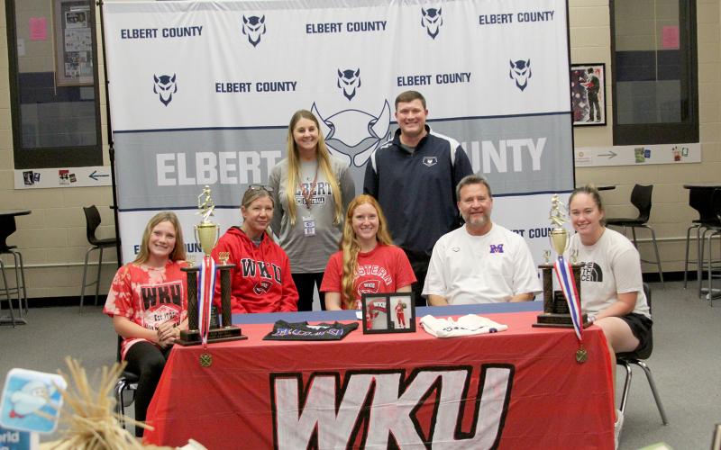 Lady Devil softball player Ava Lunsford signed to continue her softball career at Western Kentucky University Friday, Nov. 11 at Elbert County Comprehensive High School. Pictured during the signing ceremony are (front row, L-R) sister Audrey Lunsford, mom Karol Lunsford, Lunsford, dad Mike Lunsford and sister Elle Luns-ford; (back row, L-R) Coach Bria Bush and Head Coach Drew Greer. (Photo by Wells)
