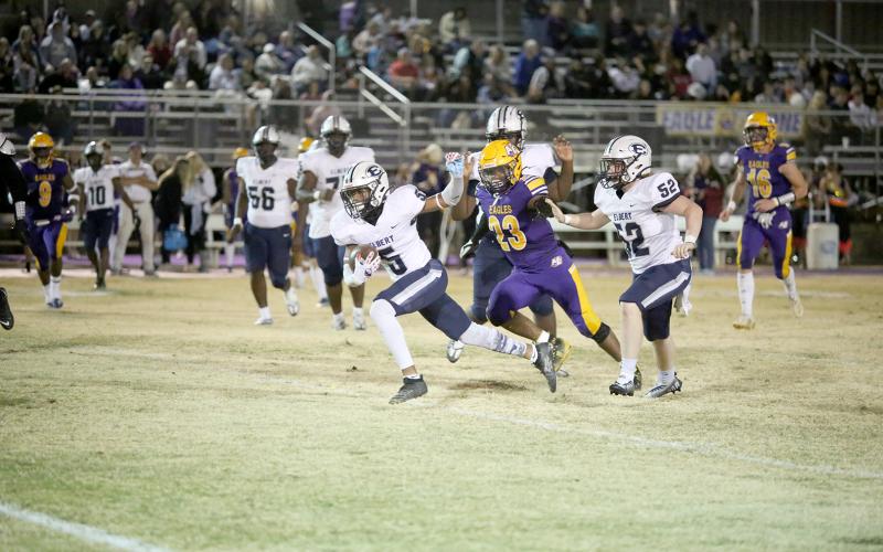Trustin Allen (No. 5) racks up yards during the game as Eli Jourolmon (No. 52) prepares to ward off an Eagle defender. (Photo by Scoggins)
