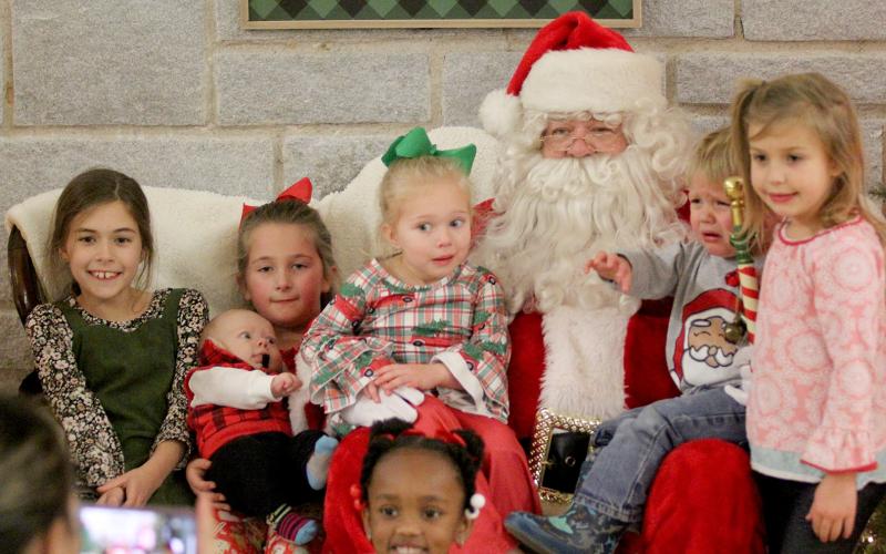 Santa Claus stopped by the Historic Rock Gym to visit families from the Elbert County Sheriff’s Office Thursday, Dec. 17 and received mixed reactions during picture time. Pictured with Santa are (front row) Ariyah Heard and (second row, L-R) Zoey Allen, Madelyn Frady and Lawson Dove, Hadley Frady, Kamdyn Harris, and Kendal Harris. (Photo by Wells)