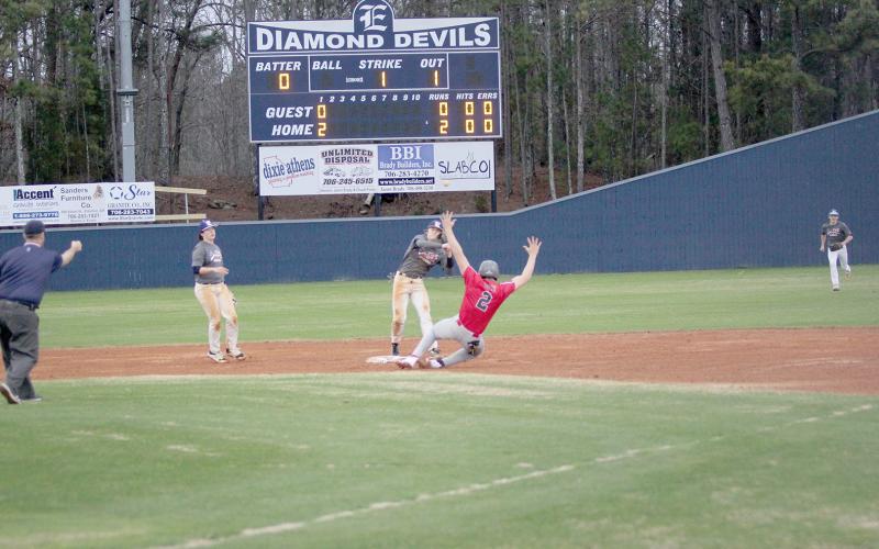 Eli Harris throws the ball towards first base as a Madison County runner slides into second during the Devils’ season-opening scrimmage against the Red Raiders Jan. 31. The Diamond Devils are kicking off the season as the No. 9 team in the state for the AA classification and are coming off last year’s region championship-winning season. The regular season kicked off Monday against Habersham. (Photo by Wells)