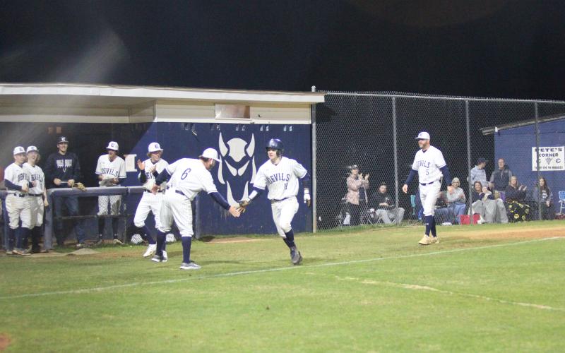 Head Coach Lance Ingram (left) congratulates Skylar Bray (right) as he runs home after knocking out a grand slam during the Devils’ 9-4 win over Hart County Feb. 8 at Diamond Devil field. (Photo by Wells)