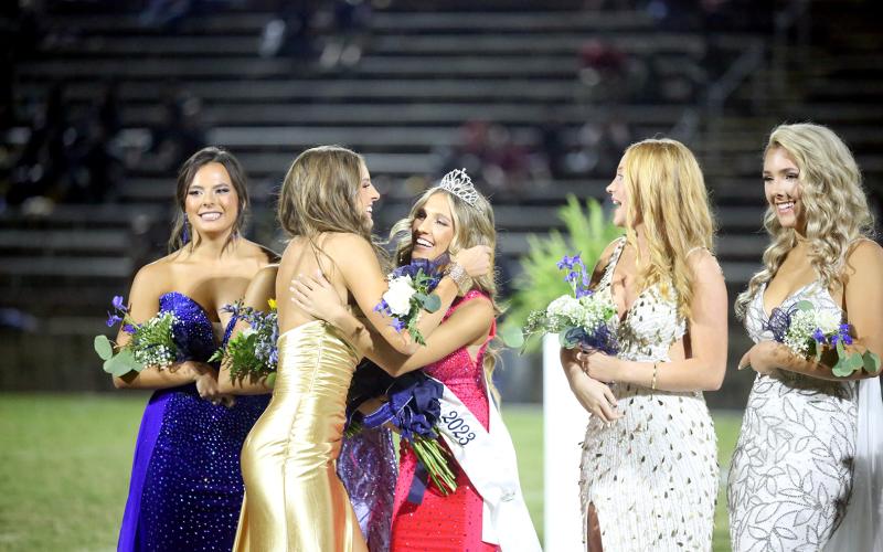 Senior homecoming court representatives Cile Hall (far left) and Jude Sanders (far right) look on as junior homecoming court representative Hannah Brady (second from left) embraces her cousin, Gracie Brady, after Gracie was crowned the 2023 Elbert County Comprehensive High School homecoming queen during halftime of the Elbert County Blue Devils football game Sept. 22 in the Granite Bowl. (Photo by Wells)