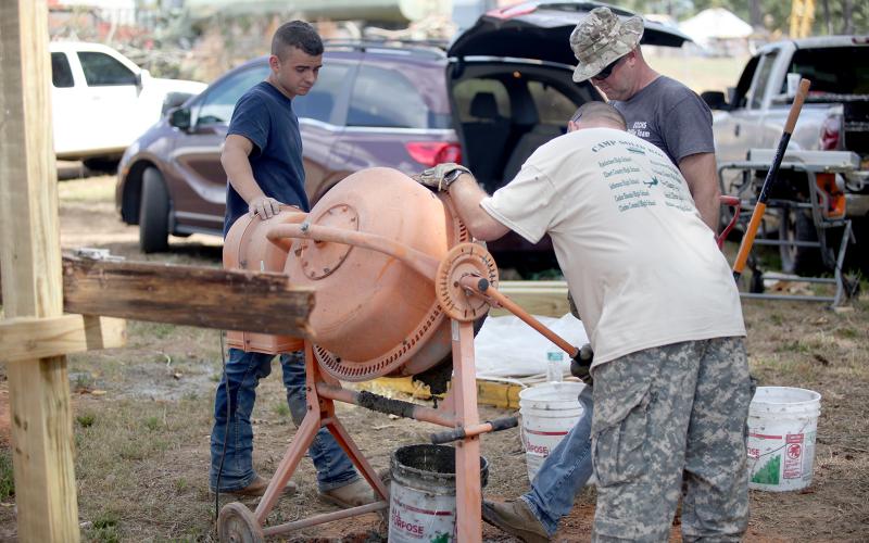 Colton Mabry (left), Sgt. 1st Class Otis Cadd (top right) and Sgt. 1st Class Dan Ulrich (bottom right) mix cement for the JROTC program’s new obstacle course at Elbert County Comprehensive High School Oct. 6. (Photo by Wells)