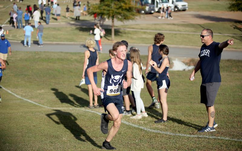 Head Coach Kyle Ashworth points up the track as Ezra Adamson runs by during the Region 8A Division 1 championship meet. (Photo by Wells)