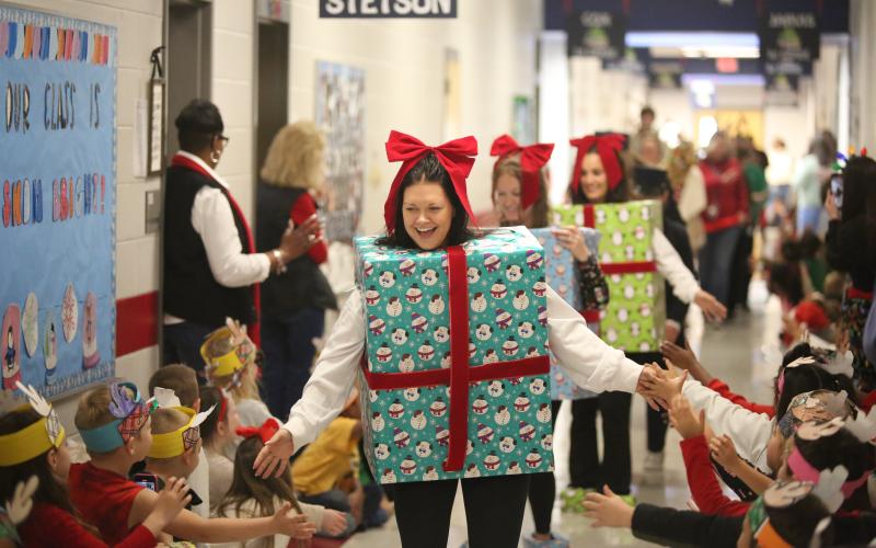 Elbert County Primary School (ECPS) first grade teachers (front to back) Ashley Mills, Brianna Bowen and Kaitlin Walker high five students while dressed as presents during the ECPS Christmas Parade Dec. 13. The parade included teachers and faculty dressed up in festive Christmas attire and included a special visit from Santa Clause himself. (Photo by Wells)