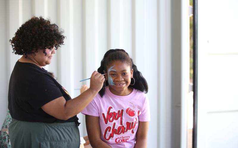 A student with the Lamar Dodd School of art paints faces during an event held at Beaverdam Marina June 8. (Photo by Wells)