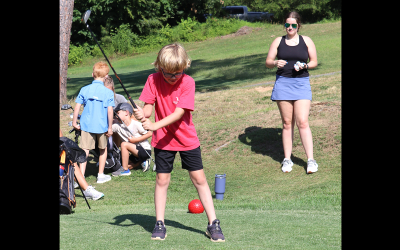 Lincoln Wade (left) drives off the tee box while former Lady Devil golfer Emalise Andrews (right) looks on. (Photo by Weeks)