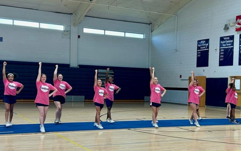 The Lady Rams football squad demonstrates a new cheer they learned to help cheer on the 2024 Rams football team. Above right, Jaray Harris (top) flies with her new stunt group. (Photo submitted by Jamie Keblish