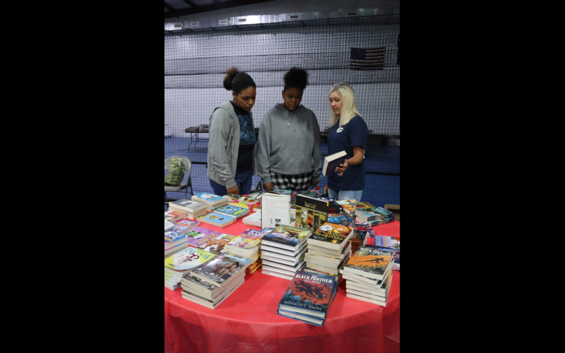 During the Pleasant Grove Baptist Back to School Bash Elbert County Comprehensive High School senior Nathalia Aquino and Elbert County Middle School eighth grader Nalleoi Aquino discuss book titles with Tanya Long, retired Director of Teaching and Learning for Elbert County Schools. (Photo by Weeks)