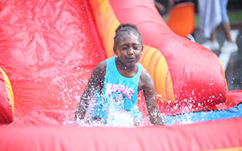 A particpant at Big Splash enjoys the water slide while enjoying the end of summer activities at the library. (Photo by Wells)