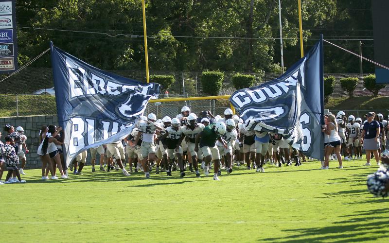 Charging through the first run-through sign of the season, the ECCHS Blue Devils take the field at the Friday Night Lights Community Kickoff Friday, Aug. 9 in the Granite Bowl. The Devils ran various plays and drills and had a practice scrimmage during the event while fans watched from the stands.  Also on hand this season's new cheerleading squads, band and auxiliary members and youth league football and cheerleading squads. (Photo by Weeks)