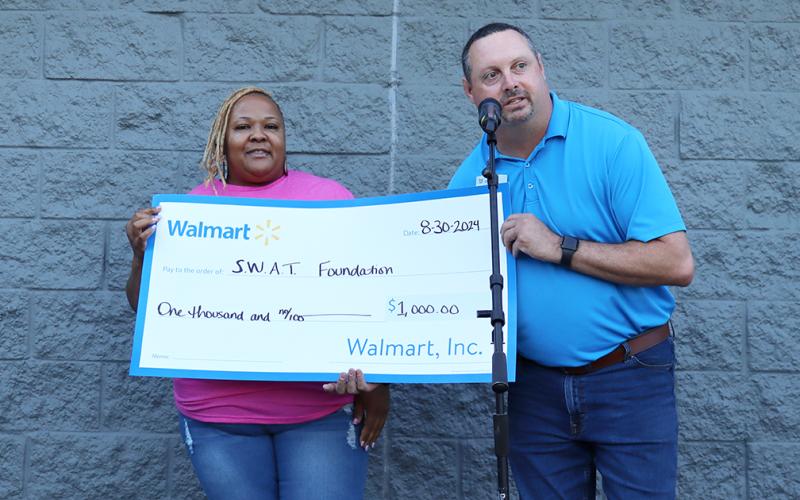 Walmart manager Alan Belford presents donation to Serving With A Testimony. (Photo by Weeks)