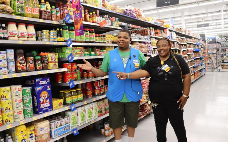 Associates Kelcey Elmore and Tyeshia Harris show the blue "new" markers customers will see throughout the store denoting new items in the various sections. (Photo by Weeks)