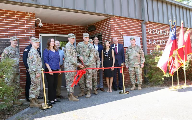 Georgia Army National Guard members along with local city, county and state officials look on as Captain Elisha Campbell and Brigadier General Jason Fryman cut the ribbon signalling the re-opening of the local National Guard Armory. (Photo by Weeks)