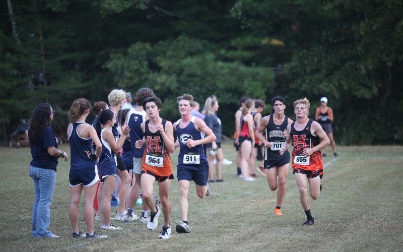 Ezra Adamson smiles while running past a group of his teammates during the first-ever Granite City Invitational Sept. 24 at Camp Harmony. Adamson finished third overall and was the highest finishing Devil at the meet. (Photo by Wells)