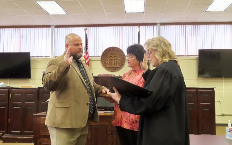 Incoming sheriff Jamie Callaway (left) is sworn in by Probate/Magistrate judge Stephanie Hewell(right) as Callaway's wife, Jill (center) assists by holding the Bible. (Photo by Weeks)