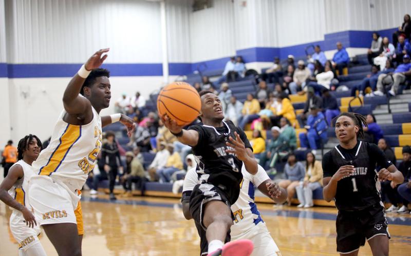 Jordan Morrison leaps as he lays the ball in with one hand in between a pair of Screaming Devil defenders during Elbert’s loss to Warren County Jan. 18. (Photo by Wells)