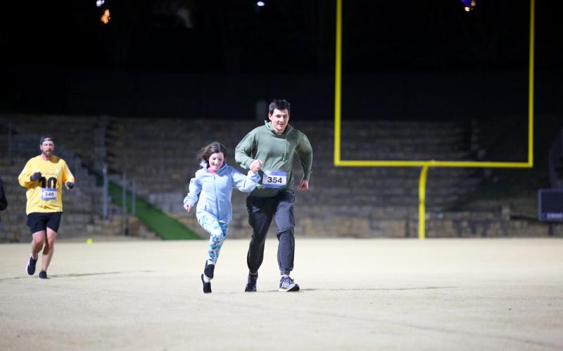 A father and daughter sprint as they approach the finish line during the Twilight Stroll Jan. 3. (Photo by Wells)