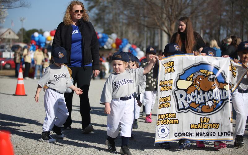 Ariel Wood of the T-ball team, the Rockhounds, helps her teammates carry their sign. (Photo by Wells)