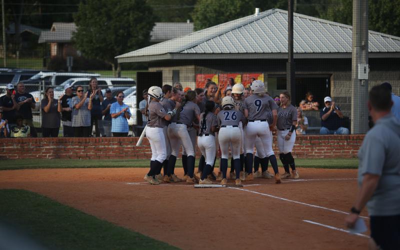 The Lady Devils softball team swarms Ky Dubose at home plate after she hit a home run in their rescheduled game against Hart County Aug. 27. (Photo by Bo Under