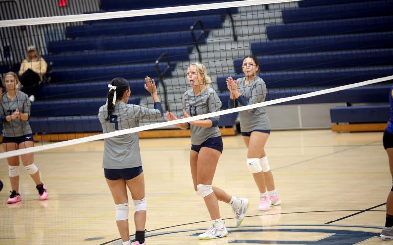 Cadence Noggle (13) celebrates a point with Ariel Moncallo (9) and Zurina Dillard (14). Photo by By Underwood)