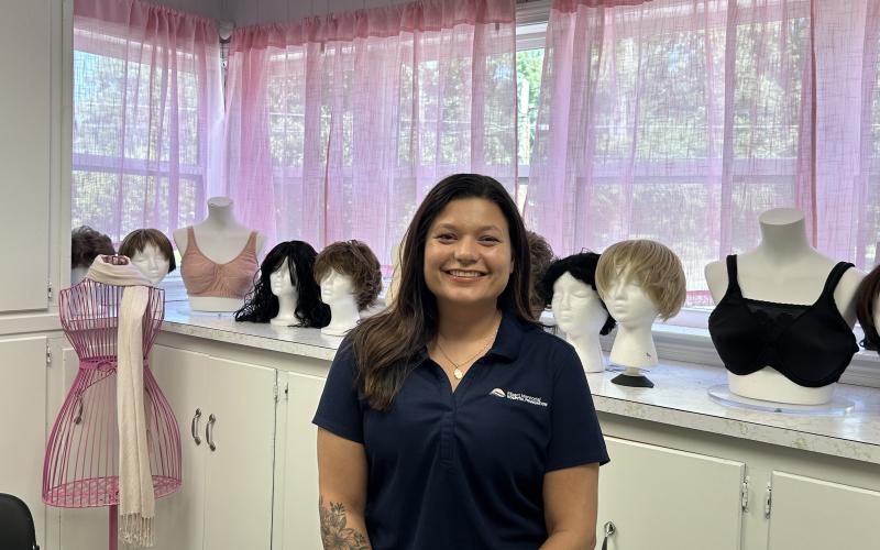 Jenny Jenkins, founder of Jenny's Boutique poses in front of some of the boutique's wig selection. (Photo by Mark Wells)