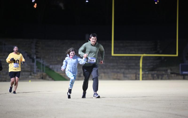 A man and girl run in the Twilight Stroll by the Granite Bowl.