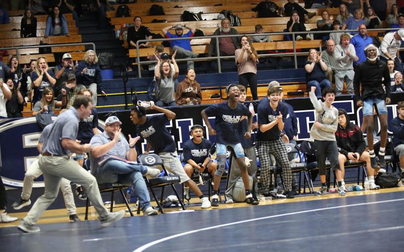 Elbert assistant coach Bryce Noggle celebrates with Elbert wrestlers on the bench