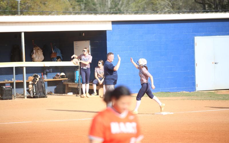Head coach Josh Jones high-fives Bellamy Nash (5) as she rounds third base following a home run. (Photo by Bo Underwood)