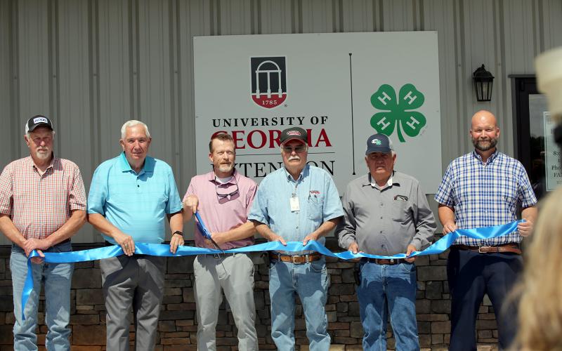 (L-R) Commissioners Mike Scoggins, David Hunt, commission chair Lee Vaughn, Commissioners Casey Freeman, Chris Alexander and county manager Allen Hulme prepare to cut the ribbon during a ceremony celebrating the grand opening of the county's new 4-H facility. (Photo by Bo Underwood)