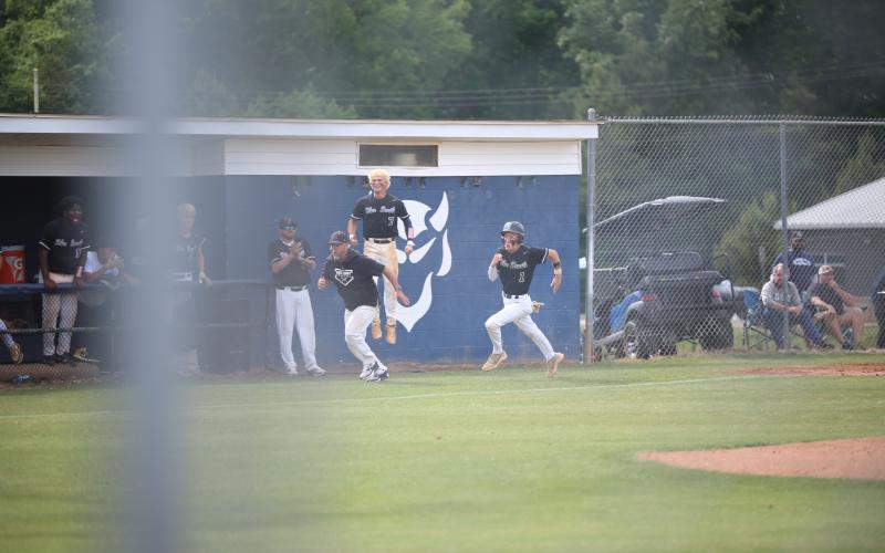 Elbert County head coach Lance Ingram (left) runs alongside shortstop Brayden Ingram (1) after sending him home as Jackson Black (7) celebrates. (Photo by Bo Underwood)