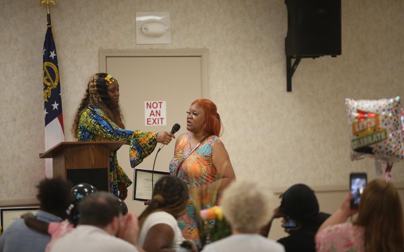 Talyra Sims gives the microphone to Sandy Wingfield at Mother to Mother's graduation ceremony. Terri Jackson receives a hug after completing Mother to Mother's 12-month recovery course. (Photo by Mark Wells)