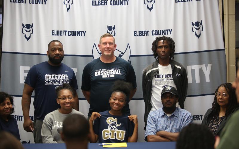 Kaylen Rucker (bottom row, middle) smiles after signing her letter of intent with Columbia International University. Rucker was joined at the table by father Clinton Rucker and mother Kristen P. Simpson, grandmother Gloria Partlow, grandmother Shelia Allen, aunt Karen Partlow Burton, Lady Devils head coach Josh Jones and assistants Donald Bolton and James Allen. (Photo by Bo Underwood)