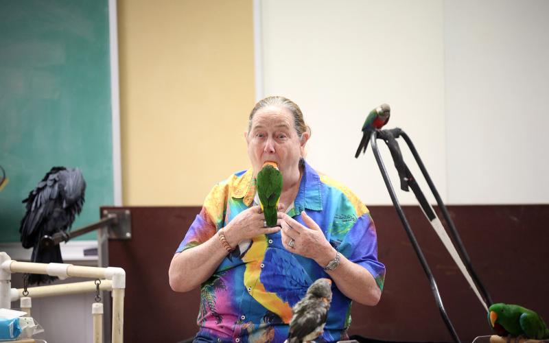 One of the many tricks Brenda Bean of Parrot Productions has perfected is putting one of her bird's full heads in her mouth. The trick was part of Tropical Birds with Bean and Bird at the Elbert County Public Library. (Photo by Bo Underwood)