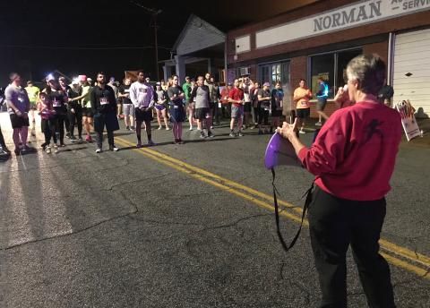 Carol Baker, whose company (Classic Race Services) times runners for the Twilight Stroll, gives instructions to runners before the 5K start. (Photo by Jones)